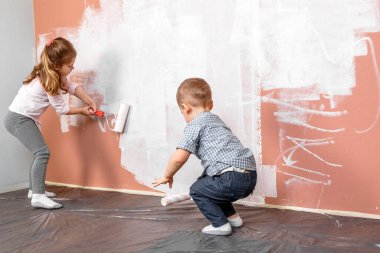 Küçük güzel ve mutlu çocuk evdeki fırçayla duvarı boyuyor.