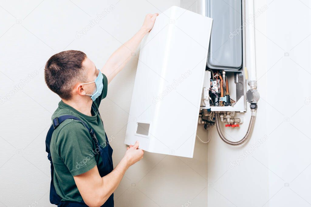 Plumber attaches Trying To Fix the Problem with the Residential Heating Equipment. Repair of a gas boiler