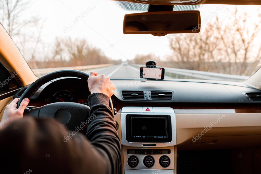 The young man driving the modern car on asphalt road