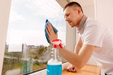 Ofisin camlarını temizleyen genç adam.