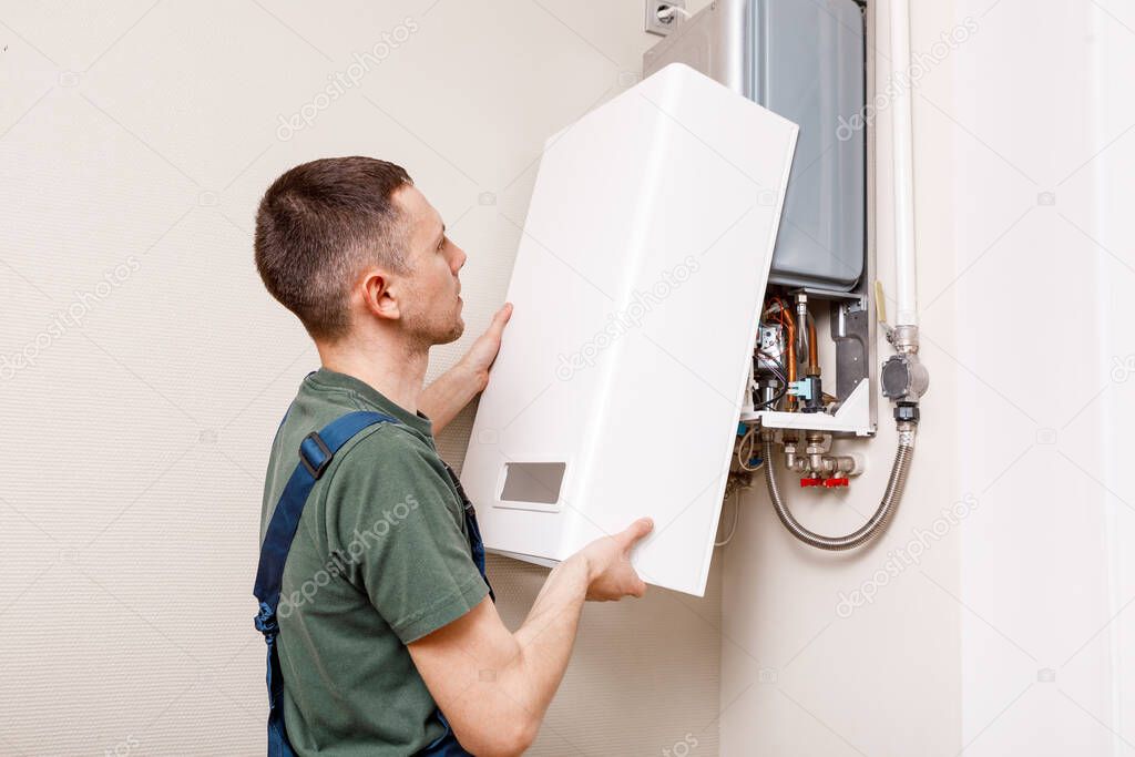 Plumber attaches Trying To Fix the Problem with the Residential Heating Equipment. Repair of a gas boiler