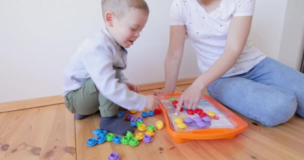 Mulher ensina criança a resolver quebra-cabeças. — Vídeo de Stock