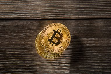 Ahşap zemin üzerinde bitcoin, dalgalanma ve ethereum sembollü gümüş ve altın sikkeler.