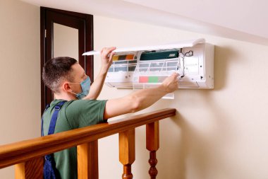 Erkek teknisyen içeride klimayı temizliyor.