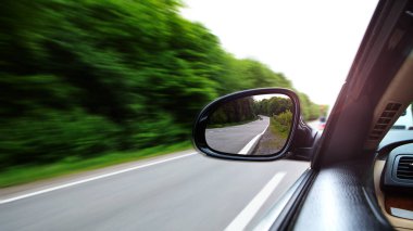 Araba boş yolda gidiyor ve aynaya odaklanıyor.