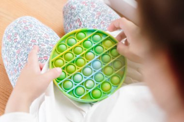 Çocuk Pop It ile oynuyordu. Gökkuşağı Kıpır kıpır oyuncak 