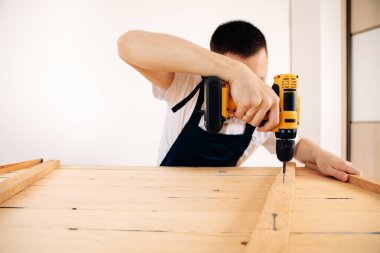 Mavi üniformalı tamirci otomatik tornavidayla çalışıyor. Ev yenileme konsepti.