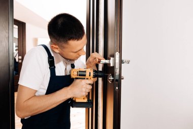 Mavi üniformalı tamirci otomatik tornavidayla çalışıyor. Ev yenileme konsepti.