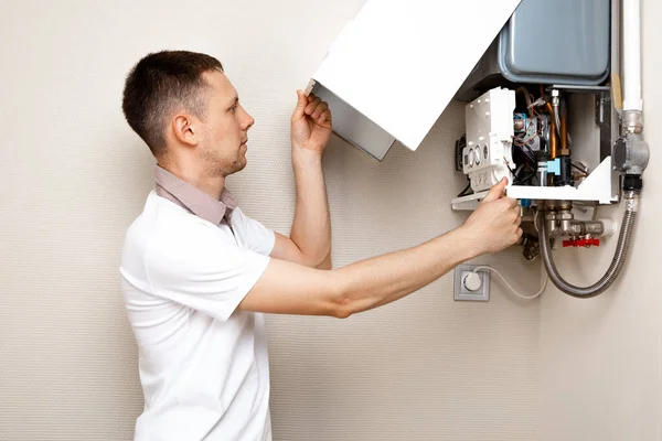 Plumber attaches Trying To Fix the Problem with the Residential Heating Equipment. Repair of a gas boiler