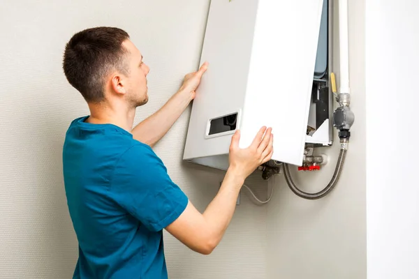 Plumber attaches Trying To Fix the Problem with the Residential Heating Equipment. Repair of a gas boiler