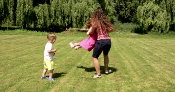 Madre jugando y divirtiéndose con su pequeño bebé sol cálido día de verano en el parque de la ciudad — Vídeos de Stock