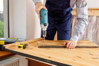 Mavi üniformalı tamirci otomatik tornavidayla çalışıyor. Ev yenileme konsepti.