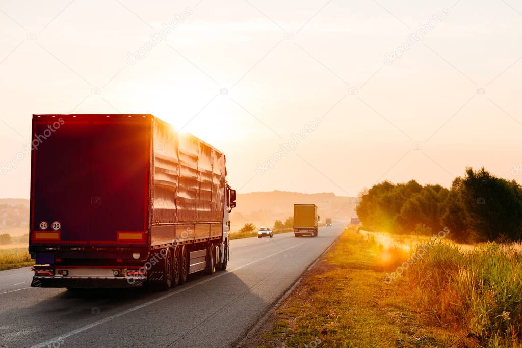 Arriving truck on the road in a rural landscape at sunset