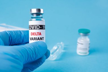 Kadın doktor elinde şırınga ve COVID 19 delta varyant aşısını mavi arka planda tutuyor. Sağlık ve Tıp Konsepti.