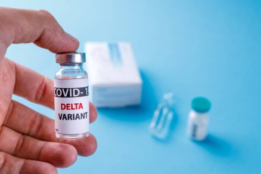 Kadın doktor elinde şırınga ve COVID 19 delta varyant aşısını mavi arka planda tutuyor. Sağlık ve Tıp Konsepti.