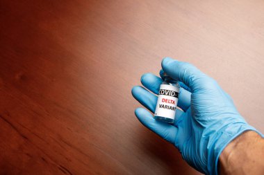 Kadın doktor elinde şırınga ve COVID 19 delta varyant aşısını mavi arka planda tutuyor. Sağlık ve Tıp Konsepti.