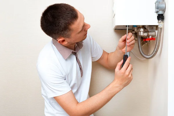 Plumber attaches Trying To Fix the Problem with the Residential Heating Equipment. Repair of a gas boiler