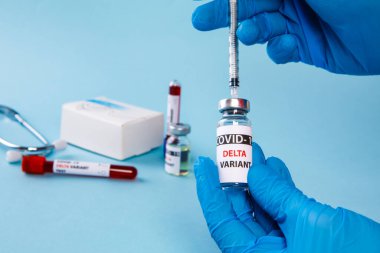 Covid 19 Delta Varyant aşısı ve mavi arka planda elde bulunan kan testi. Koronavirüse karşı aşı 
