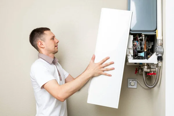 Plumber attaches Trying To Fix the Problem with the Residential Heating Equipment. Repair of a gas boiler