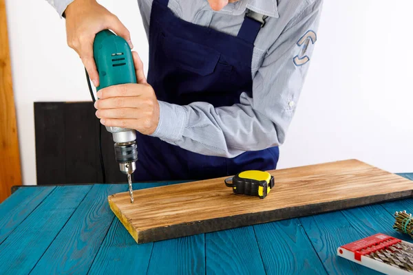 Handyman in blue uniform works with electricity automatic screwdriver. House renovation conception.