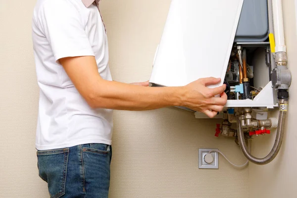 Plumber attaches Trying To Fix the Problem with the Residential Heating Equipment. Repair of a gas boiler