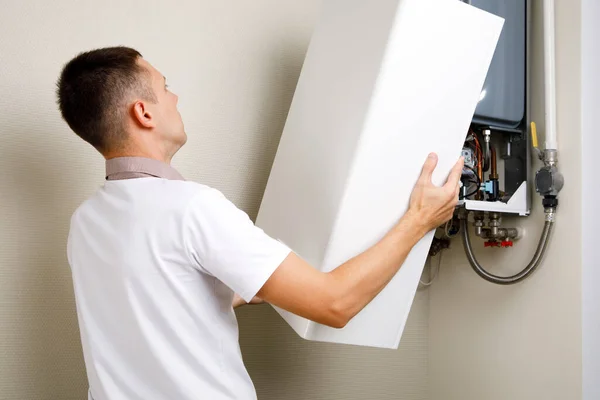 Plumber attaches Trying To Fix the Problem with the Residential Heating Equipment. Repair of a gas boiler