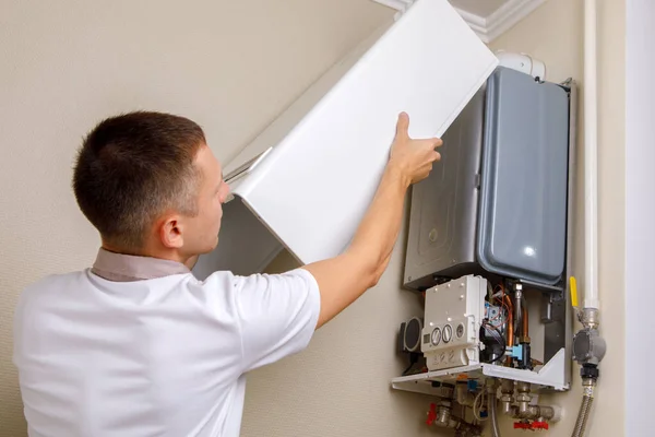 Plumber attaches Trying To Fix the Problem with the Residential Heating Equipment. Repair of a gas boiler