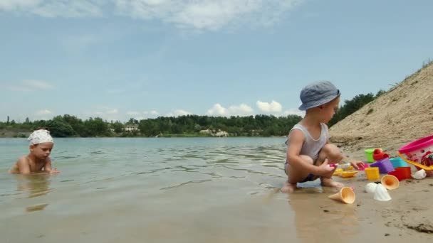 子供たちは水の近くに砂の城を建てる 幸せな夏の休日 — ストック動画