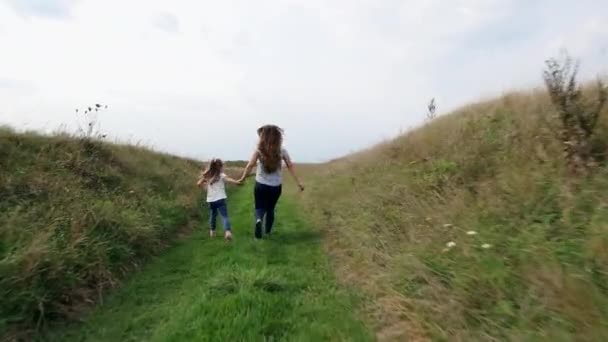 Matka i dziecko biegną trzymając się za ręce na trawie — Wideo stockowe