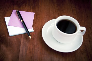 Boş beyaz porselen fincan kahve ve kalem ile kahverengi üzerine notlar