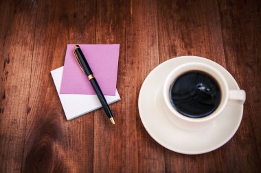 Boş beyaz porselen fincan kahve ve kalem ile kahverengi üzerine notlar