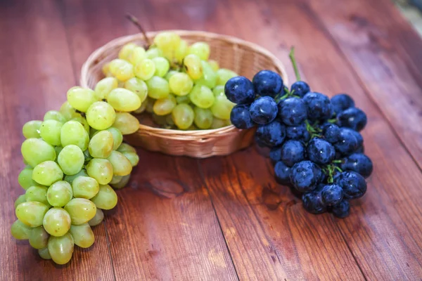 Green and purple round grapes on old wooden table, selective foc