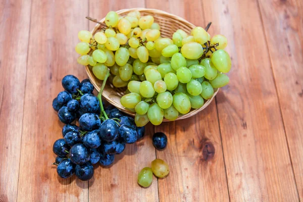 Green and purple round grapes on old wooden table, selective foc — Stock Photo, Image