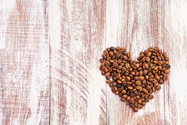 Forma de corazón hecha de granos de café en la superficie de madera. —  Fotos de Stock