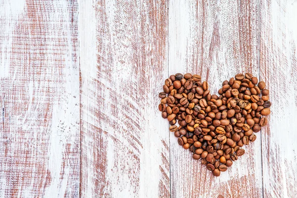 Forma de corazón hecha de granos de café en la superficie de madera. —  Fotos de Stock