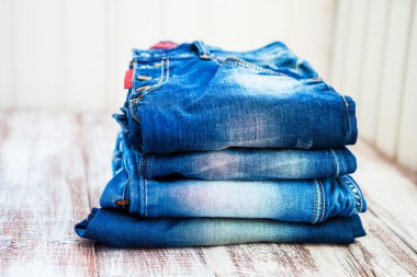 Ahşap arka planda üst üste dizilmiş kot pantolon