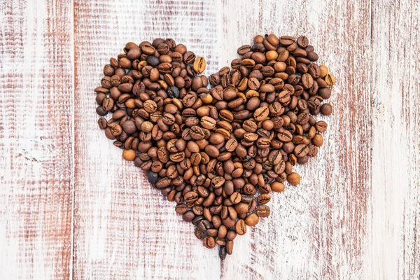Forma de corazón hecha de granos de café en la superficie de madera. —  Fotos de Stock