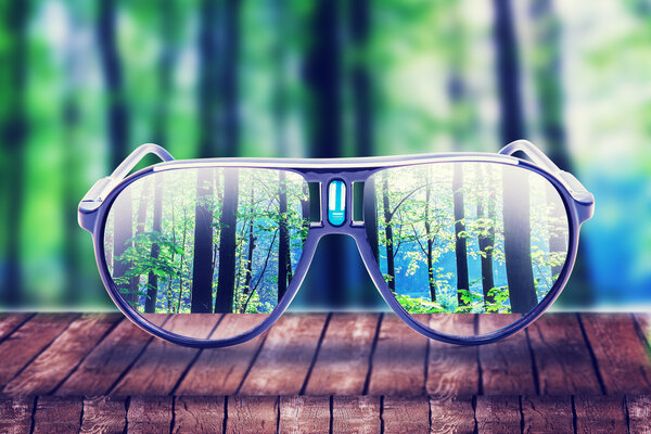 hipster glasses on a park bench or table with a forest
