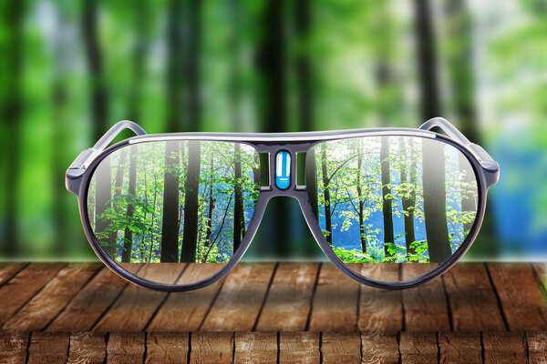 hipster glasses on a park bench or table with a forest