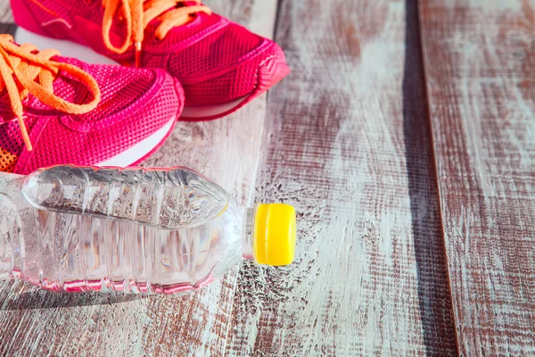 Zapatillas de deporte rosadas y botella de agua — Foto de Stock