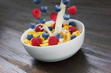 Falling corn flakes with fresh berries and pouring milk clipart