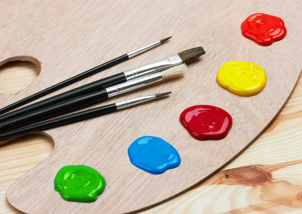 Paleta de arte de madeira com tintas e pincéis — Fotografia de Stock