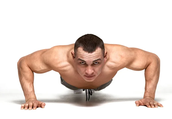 Hombre muscular haciendo flexiones en el estudio sobre fondo blanco — Foto de Stock