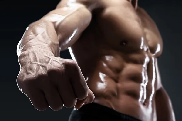 Knappe gespierde bodybuilder toont zijn vuist en ader. — Stockfoto