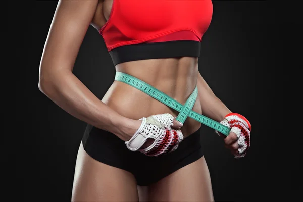 Atlética mujer delgada midiendo su cintura por cinta métrica —  Fotos de Stock
