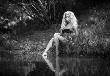 Göl kenarında oturan kadın bikini