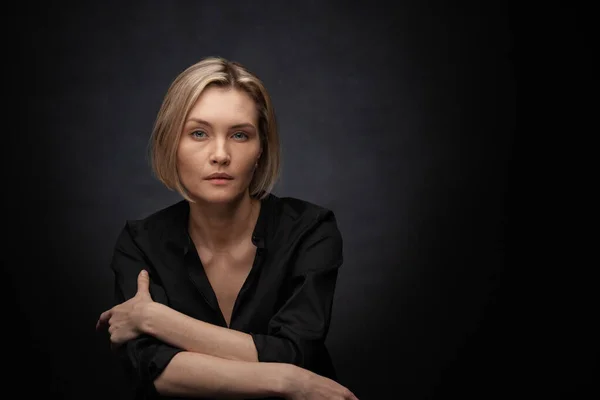 Beautiful middle-aged woman on a gray background in a black blouse. — Stock Photo, Image