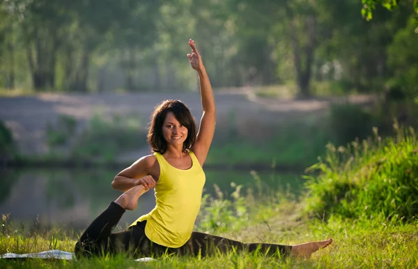 Vrouw voert yoga oefeningen en Pilates in de natuur — Stockfoto