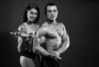 Athletic man and woman with a dumbells clipart