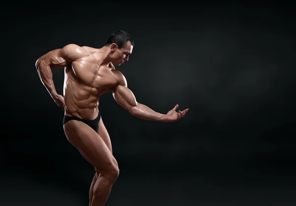 Bonito fisiculturista muscular posando sobre fundo preto . — Fotografia de Stock